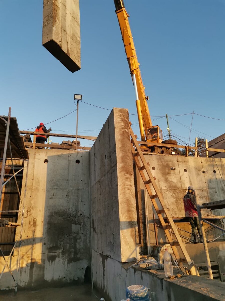 Deep reinforced-concrete wall section being removed by crane